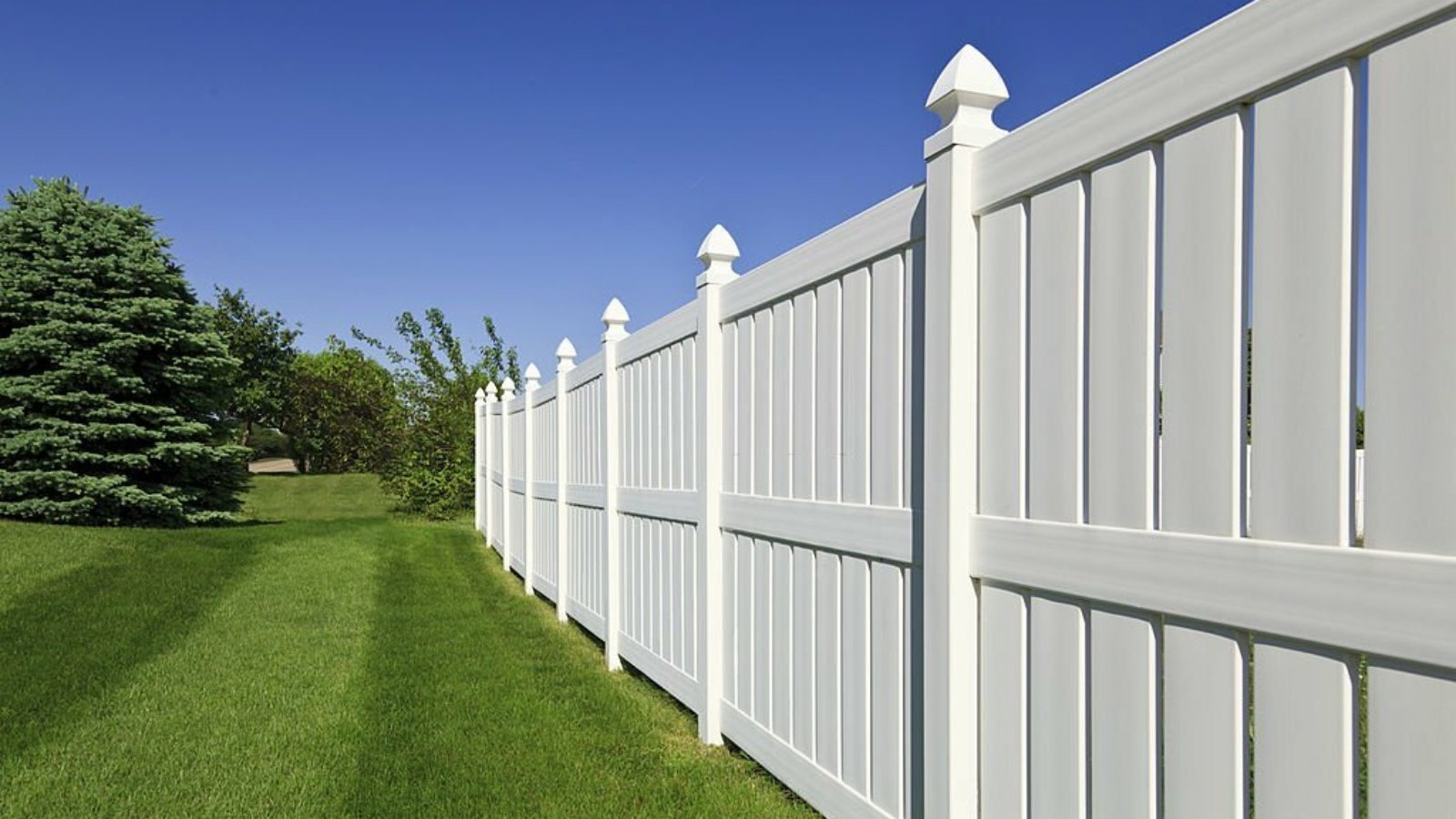 A scenic residential home with a white fence in the yard, surrounded by a beautiful blue sky and garden fencing ideas.