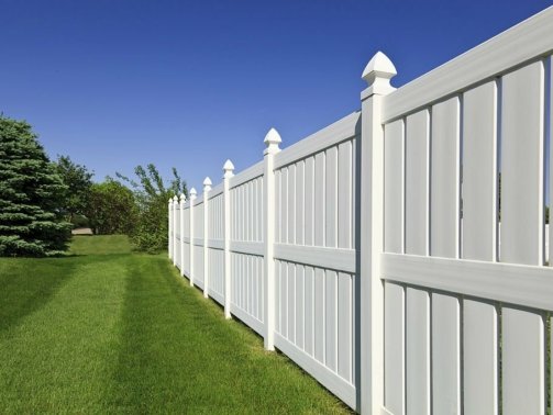 A scenic residential home with a white fence in the yard, surrounded by a beautiful blue sky and garden fencing ideas.